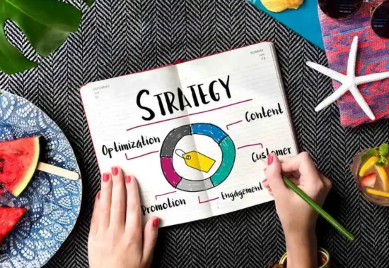 A top-down view of hands holding a printed "Strategy" diagram with a colorful wheel showing content, engagement, and optimization elements.