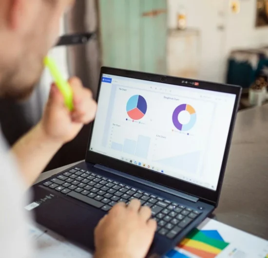 A close-up of a professional analyzing business data on a laptop and taking notes with a yellow highlighter, symbolizing strategic marketing planning.